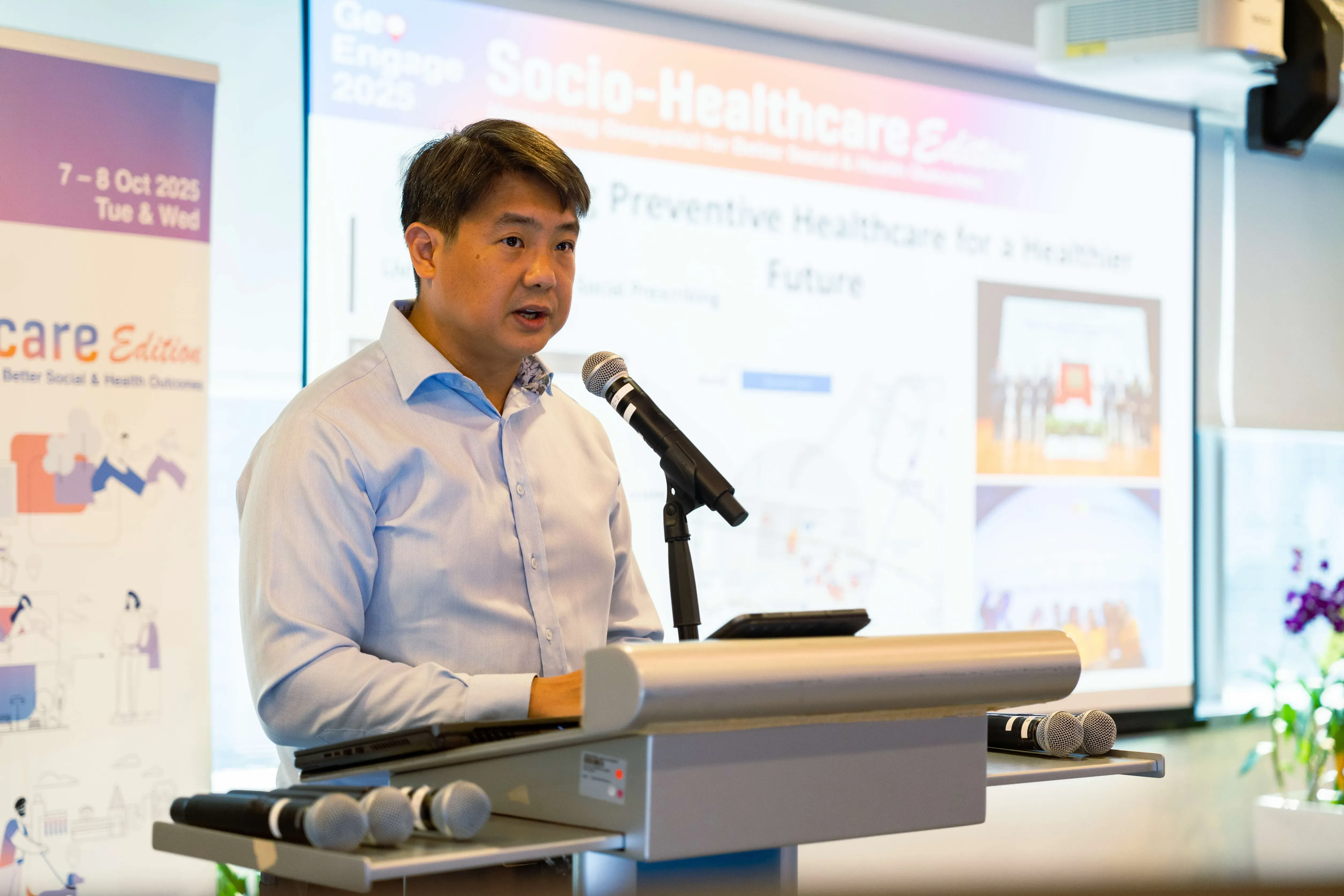 Assistant Chief Executive Mr Benjamin Chan speaks at a podium with a microphone at a Socio-Healthcare opening.